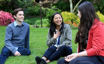 Three students sit on the lawn