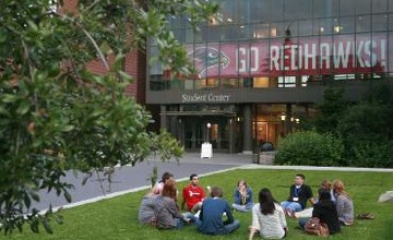 Students gathered and seated on the grass in conversation in front of Lemieux Library.