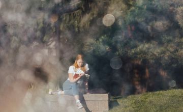 Photo of student reading by fountain