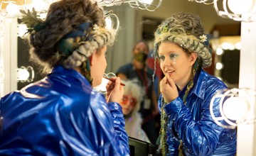 Actor putting on makeup in mirror