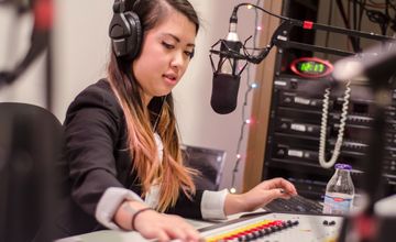 Student with a microphone and headphones in a radio setting