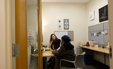 Two people sitting at a desk in an office.