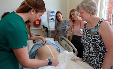 A group of people standing around a bed in a hospital.