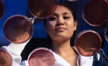 A woman in a lab coat working with petri dishes