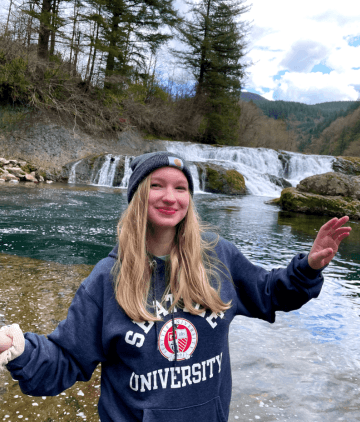 Women in Seattle University sweatshirt in front of waterfall