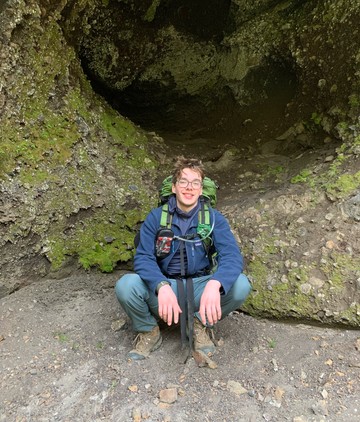 A student in front of mossy rocks.