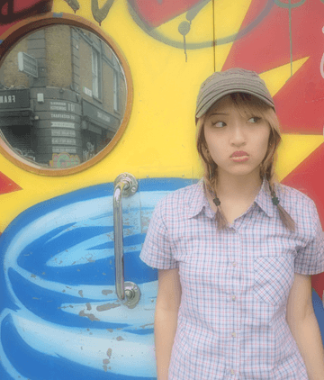 woman standing in front of a graffiti wall with a wall mirror