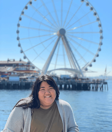 Staff mamber Kiyana Higa standing by the waterfront ferris wheel in downtown Seattle.