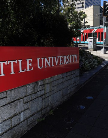 The seattle university sign is in front of a tree.