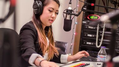 Student with a microphone and headphones in a radio setting
