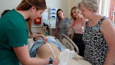 A group of people standing around a bed in a hospital.