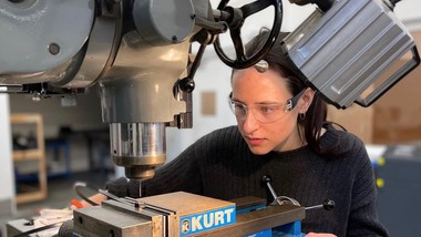 Female mechanical engineering student using a drill press