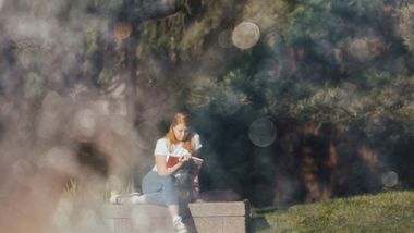 Photo of student reading by fountain
