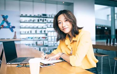 A woman writing in a notebook and looking up