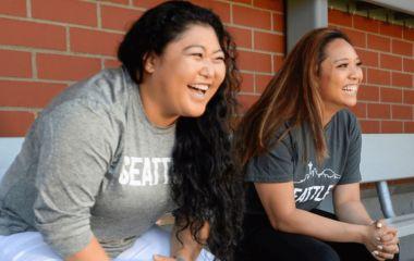 Two girls laughing while sitting on a bench
