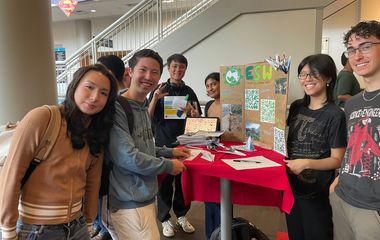 Students standing in front of a club posterboard