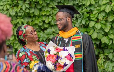 an SU graduate in regalia smiling at his parent at commencement