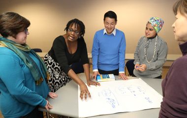 An image of a teacher working with a diverse group of graduate students.