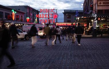 Dusk at a bustling city square with neon signs and pedestrians.