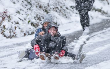 Children sledding down a snowy slope.