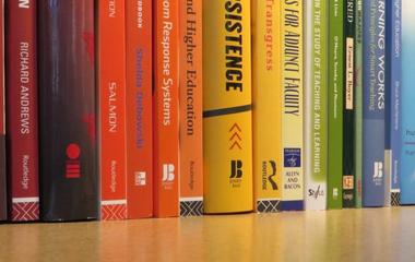 Books from the Center's library with spine colors spanning the rainbow