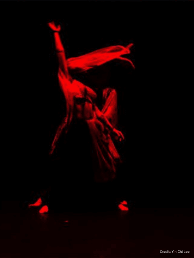 two people dancing in red light on a dark stage