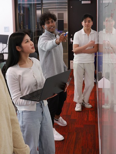 Grad students pointing at a white board