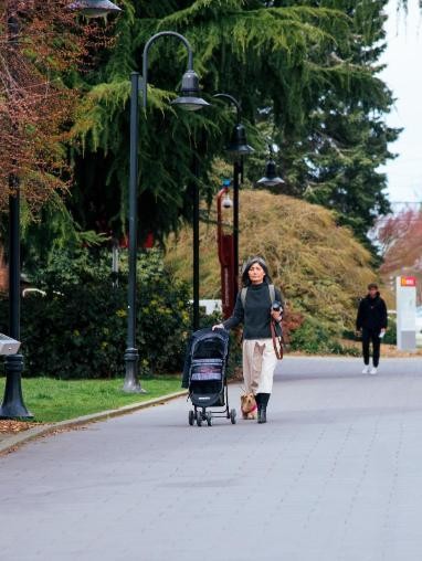 A woman pushing a stroller on a sidewalk.