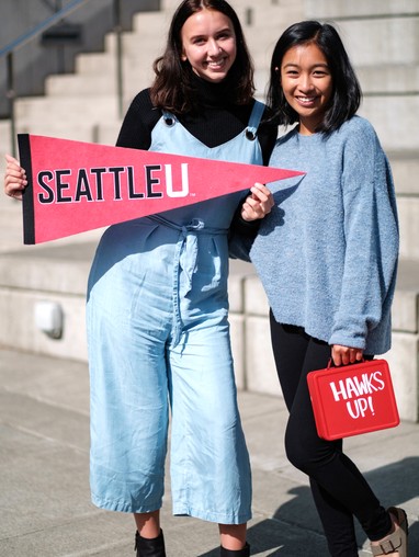 Smiling students holding SU lunch box and flag