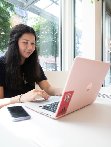 A girl sitting at a table with a laptop in front of her.