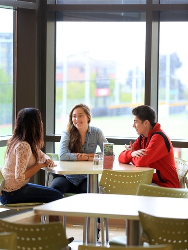 A group of people sitting at tables in a cafeteria.
