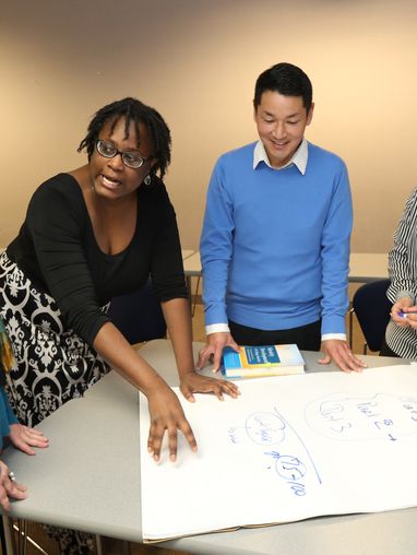 An image of a teacher working with a diverse group of graduate students.