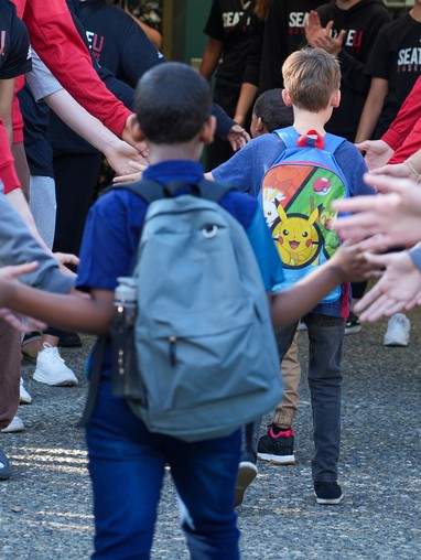 Young students passing through a high five tunnel