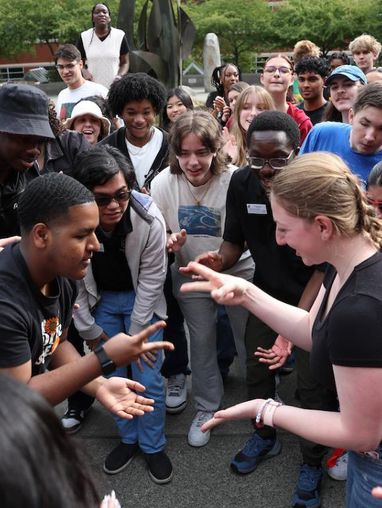 students wearing black playing an interactive hand game while smiling and laughing.