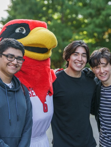 3 students smiling and posing with our mascot rudy the redhawk