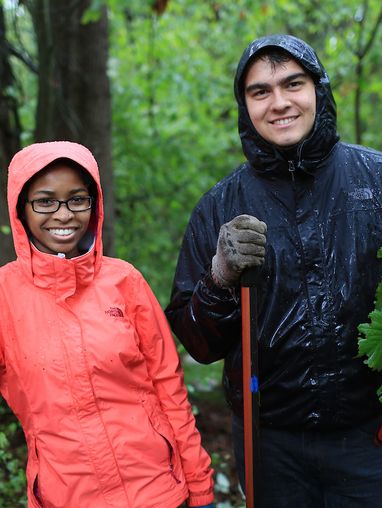 Two people in the rain doing community service