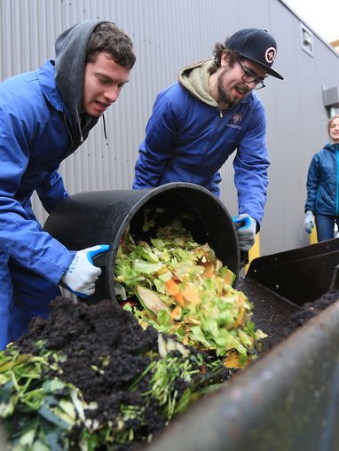 Students pouring food waste into the compact track load.