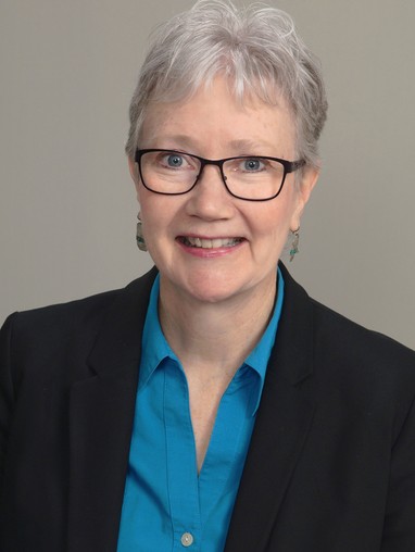 A woman wearing glasses and a blue shirt.