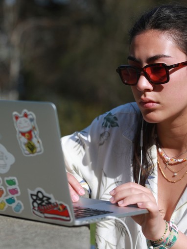 Woman wearing sunglasses looking at laptop
