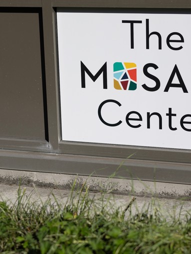 The mosaic center sign in front of a building.
