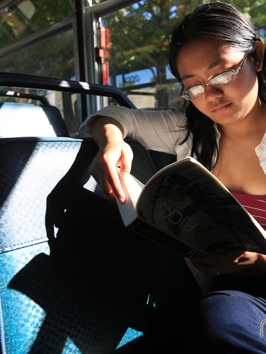 A woman reading a book on a bus.