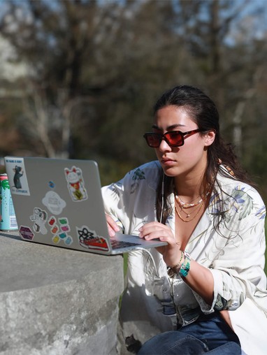 A student in sunglasses reading something on her laptop