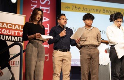Four students speaking on a stage.