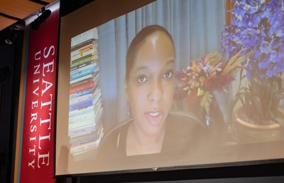 Dr. Imani Perry speaking, displayed on a large screen.