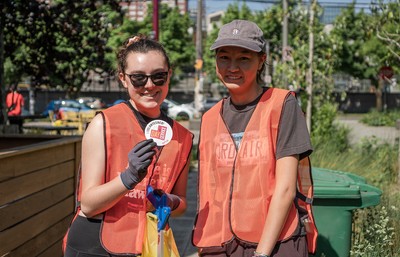 Two volunteers hold up Day of Service button at clean-up event