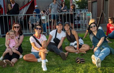 Alumni and family members smile at camera while lounging on the grass at GOLD block party