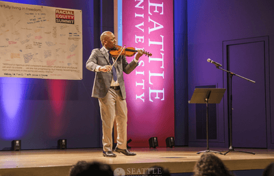 Quinton Morris playing the violin on a stage.