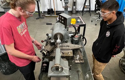 two male mechanical engineering students using a lathe