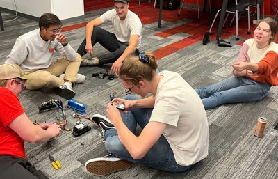 Group of Mechanical Engineering students working in the floor of the project room on part of autonomous driving vehicle.