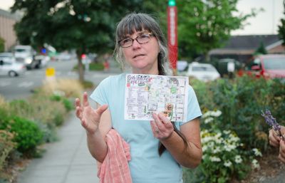 a tour guide holds up a hand-drawn map of edible campus gardens